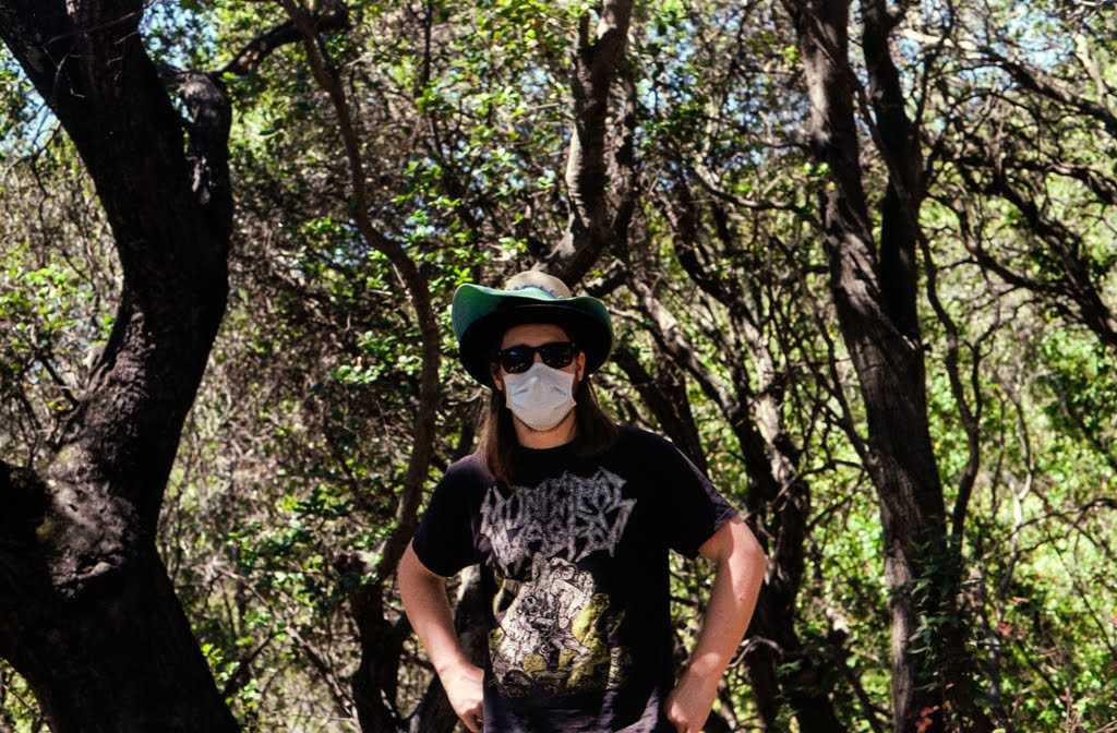 Man with strange hat standing in the woods